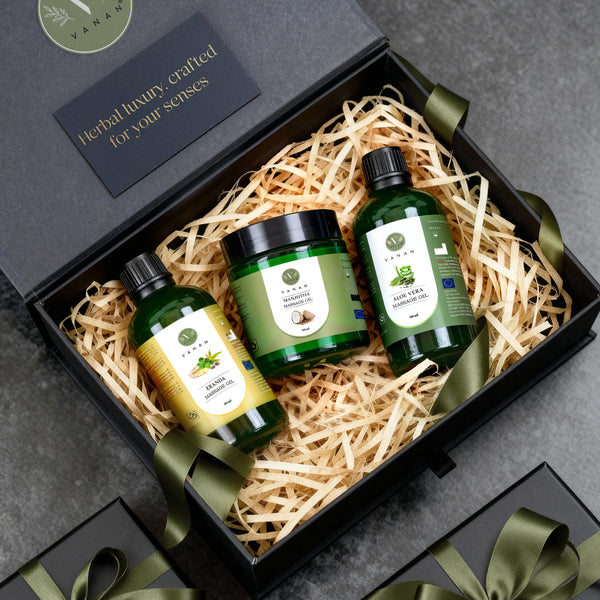 Three green bottles in a gift box with decorative ribbons on a gray surface.